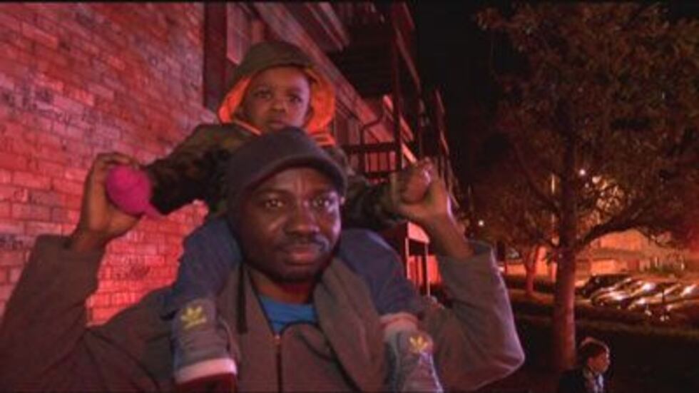 Muri Areme and one of his children waiting outside after the fire damaged their apartment.